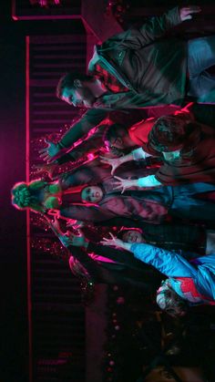 a group of people standing next to each other in front of a red light at night