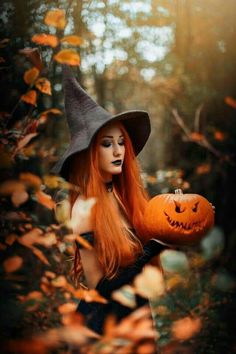 a woman with long red hair wearing a witches hat and holding a pumpkin in her hand