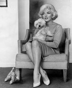 an old black and white photo of a woman sitting in a chair holding a dog