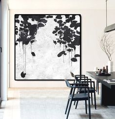 a black and white painting hanging on the wall in a dining room next to chairs