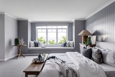 a bedroom with gray walls, white bedding and pillows on the windows sill