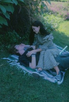 two people laying on a blanket in the grass