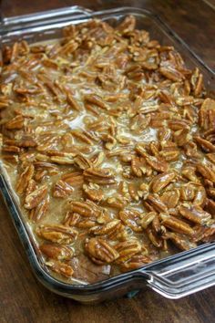 a casserole dish filled with pecans on top of a wooden table