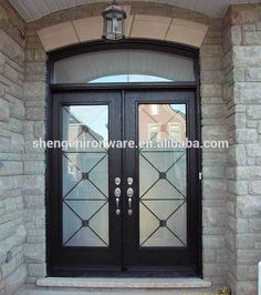 a black double door with glass on the side of a brick building in front of a light fixture