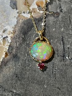 An amazing opal pendant with beautiful play of color! Set in a handmade 14k gold oval crown-style setting and adorned with a red spinel accent stone, this pendant is extremely elegant looking and mesmerising. Main Stone: natural untreated Opal Size: 11.3 x 9.4mm Weight: 3.75 carats Setting: 14k Solid Gold Accent Stone: Natural red spinel (3.5mm) Listing is for standalone pendant. Necklace can be purchased as an add-on option: - Add 925 Sterling Silver Gold Plated Necklace 30) - Add 14k solid gol Dark Water, Red Spinel, Solid Gold Necklace, Gold Accent, Brass Jewelry, Opal Pendants, Jewelry Inspo, Gold Plated Necklace, Natural Opal