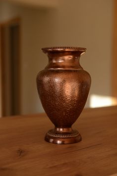 a brown vase sitting on top of a wooden table