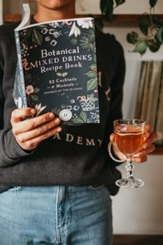 a woman holding a book and a glass of wine