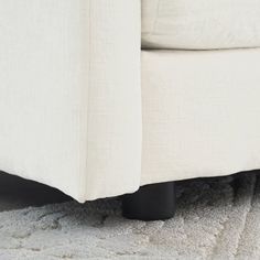 a close up view of a white couch with black legs and foot rests on the carpet