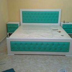 a white bed with green headboard and drawers in a room that appears to be empty