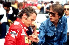 two men sitting next to each other on top of a race track with people in the background