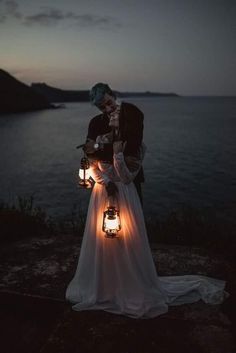 a bride and groom standing next to each other with lanterns in their hands