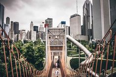 two people walking across a suspension bridge in the city