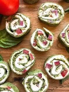 spinach rolls on a wooden board with tomatoes and basil