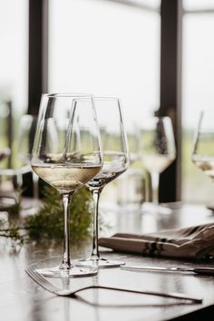 three wine glasses sitting on top of a wooden table