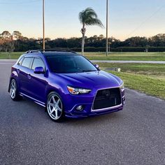 a purple car is parked on the side of the road in front of palm trees