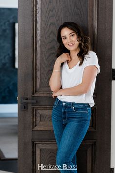 a woman leaning against a door with her arms crossed