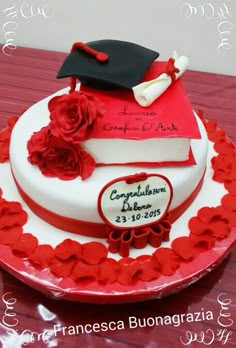 a graduation cake decorated with red flowers and a book on the top that says congratulations