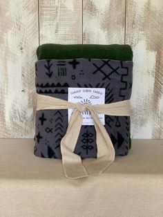 the blanket is wrapped in black and grey with an arrow design on it, along with a brown ribbon