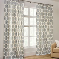 a living room with a couch, chair and window in front of the curtained windows