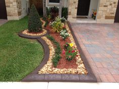 a house with landscaping in front of it and flowers on the ground next to it