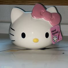 a hello kitty piggy bank with a pink bow on it's head and name tag