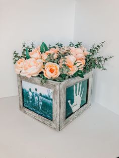 a wooden box filled with flowers on top of a white table next to a wall