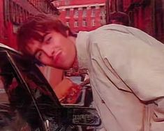 a young man leaning on the hood of a car