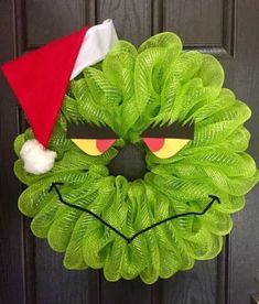 a green wreath with a red santa hat and sunglasses on it's front door