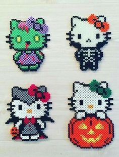 four hello kitty halloween magnets on a white table with one cat and the other kitten holding a jack - o'- lantern