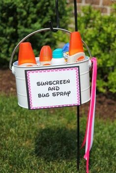 a bucket filled with baby bottles sitting on top of a grass covered field