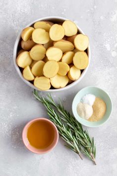 small bowls filled with potatoes and herbs next to a cup of tea on a table