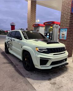 a white jeep parked in front of a gas station