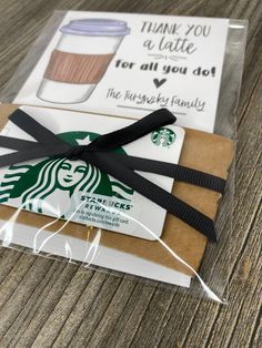 a starbucks bag wrapped in black ribbon on top of a wooden table