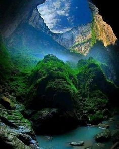 an image of a mountain stream in the middle of a cave with green trees and rocks