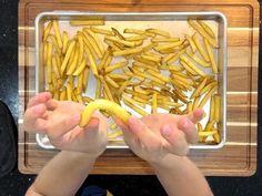 a young child holding a banana in front of a tray with bananas on top of it