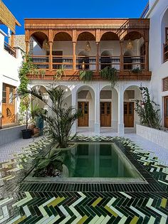 an indoor pool in the middle of a courtyard with potted plants on either side