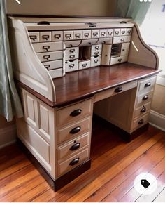 an old fashioned desk with drawers and a window in the back ground, is sitting on a hard wood floor