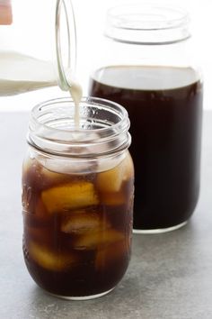 two jars filled with liquid sitting on top of a table