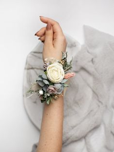 a woman's arm wearing a white rose wrist corsage