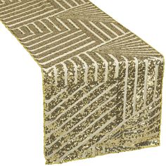 a gold and white table runner with an intricate design on the top, along with silver sequins