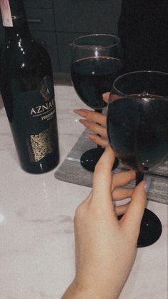 two people are toasting with wine glasses on a table next to a bottle of wine