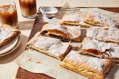 several desserts are sitting on a table next to a glass of iced coffee and two plates with pastries