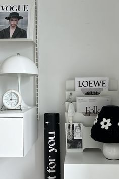 a white shelf topped with books and a lamp next to a wall mounted magazine rack