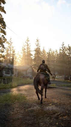 a man riding on the back of a brown horse down a dirt road next to a forest