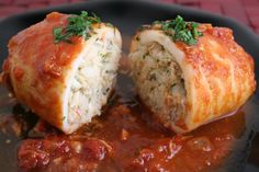 two stuffed meatballs with sauce and parsley on the side, sitting on a black plate