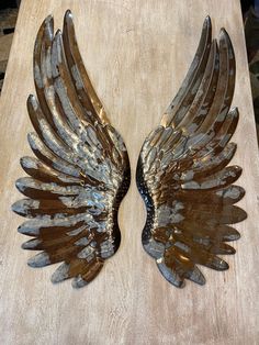 two metal wings sitting on top of a wooden table