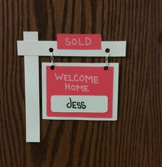 a red and white welcome home sign hanging on a wooden door with the words sold