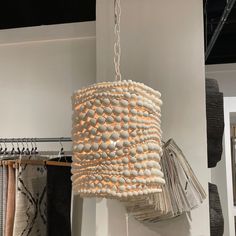 a white chandelier hanging from a ceiling in a room with clothes on hangers