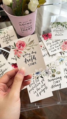 someone is holding up some cards with flowers on them and the words are written in black ink