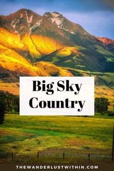 the big sky country sign is in front of mountains and green grass, with a blue sky